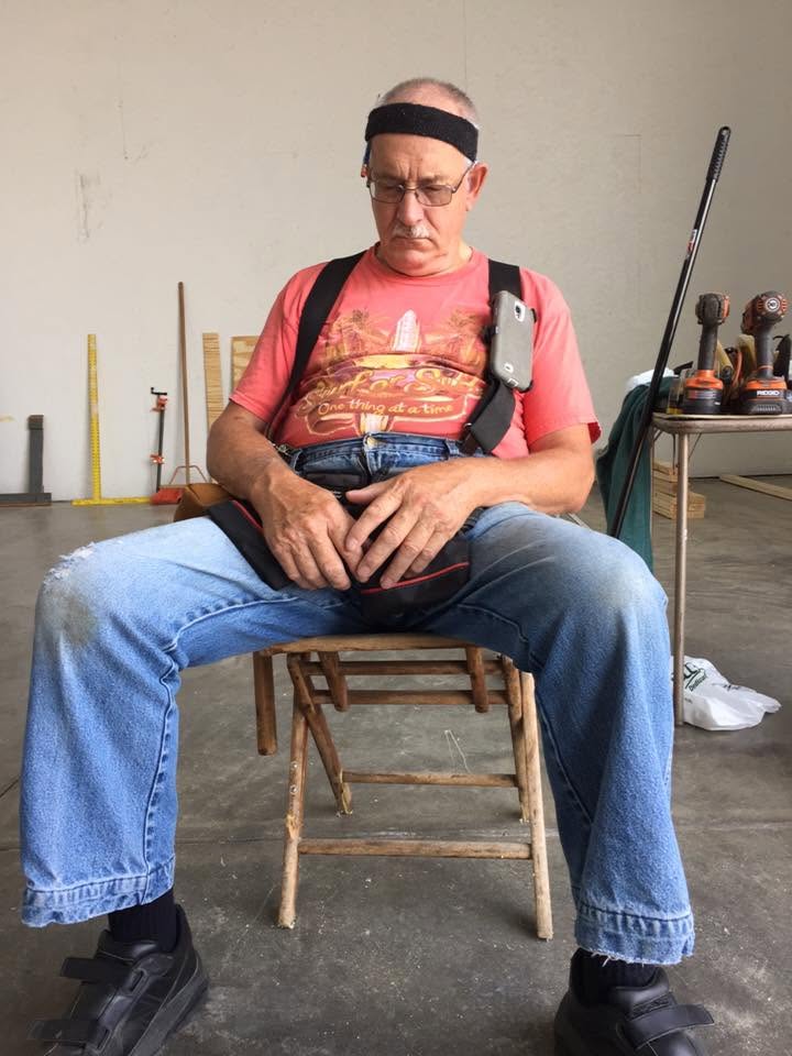 Al asleep in a folding chair on the job site, tools on the table behind him